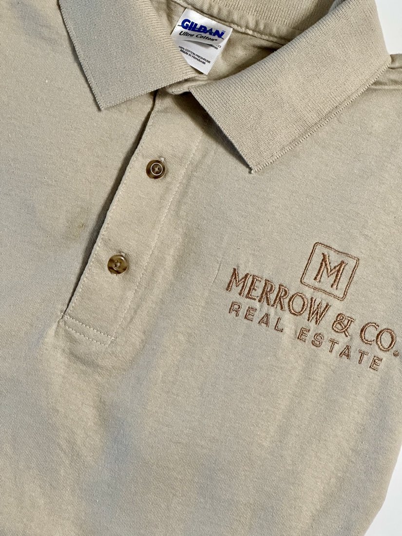 Tan polo embroidered with a real estate company logo